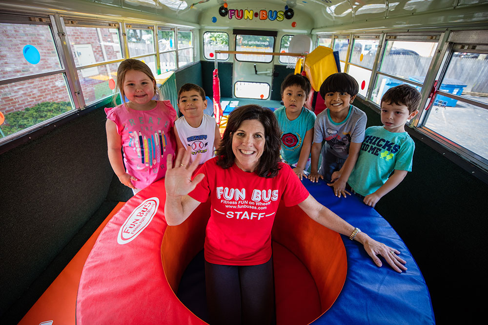FUN BUS owner smiling as she plays with children, just one of the many advantages of franchising.